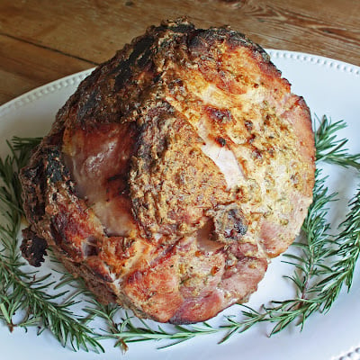 Top view of whole roasted ham with the mustard and rosemary crust clearly shown baked on. 