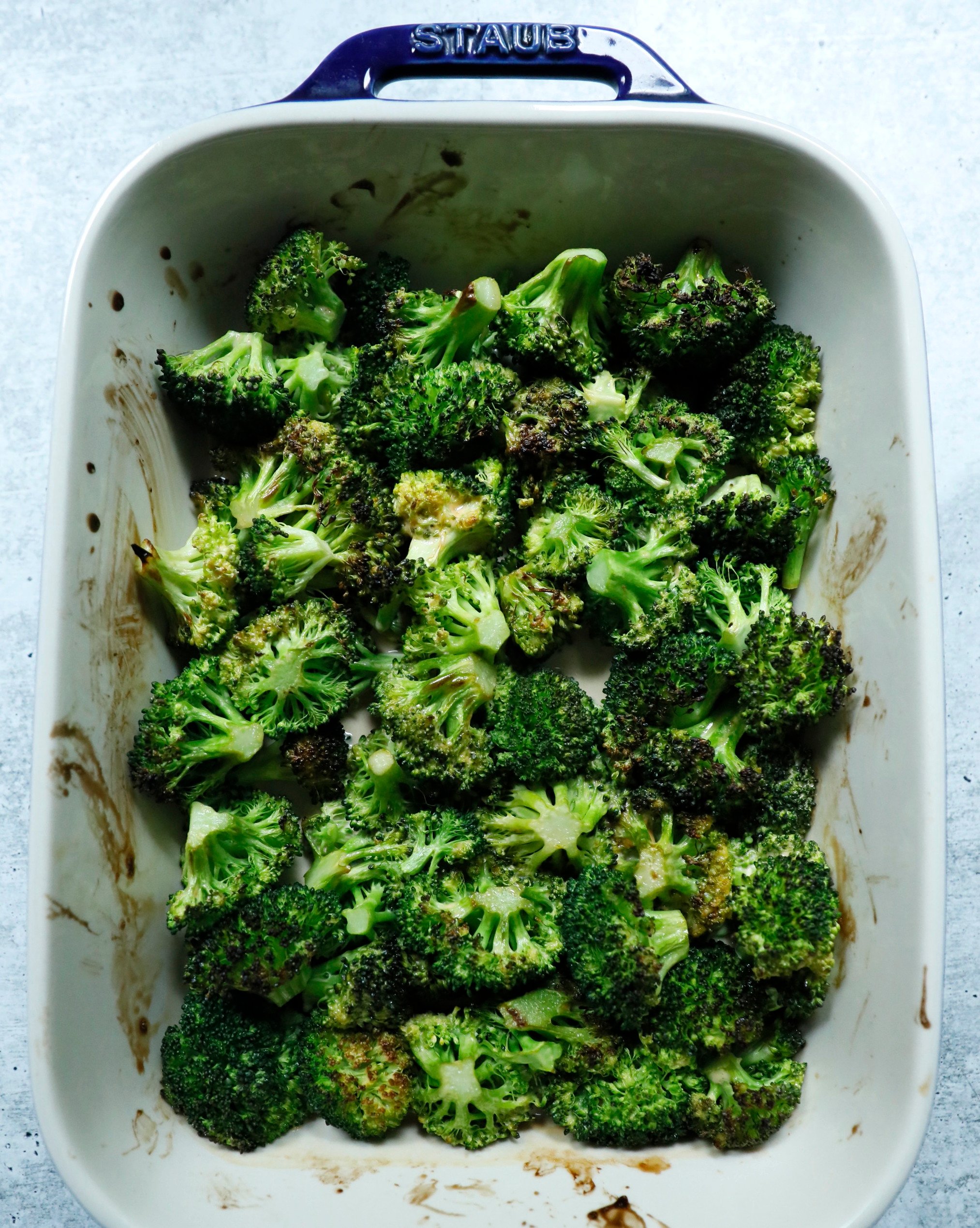 A staub casserole dish full of roasted broccoli