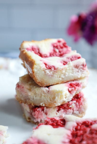 three keto raspberry cheesecake bars stacked on top of each other