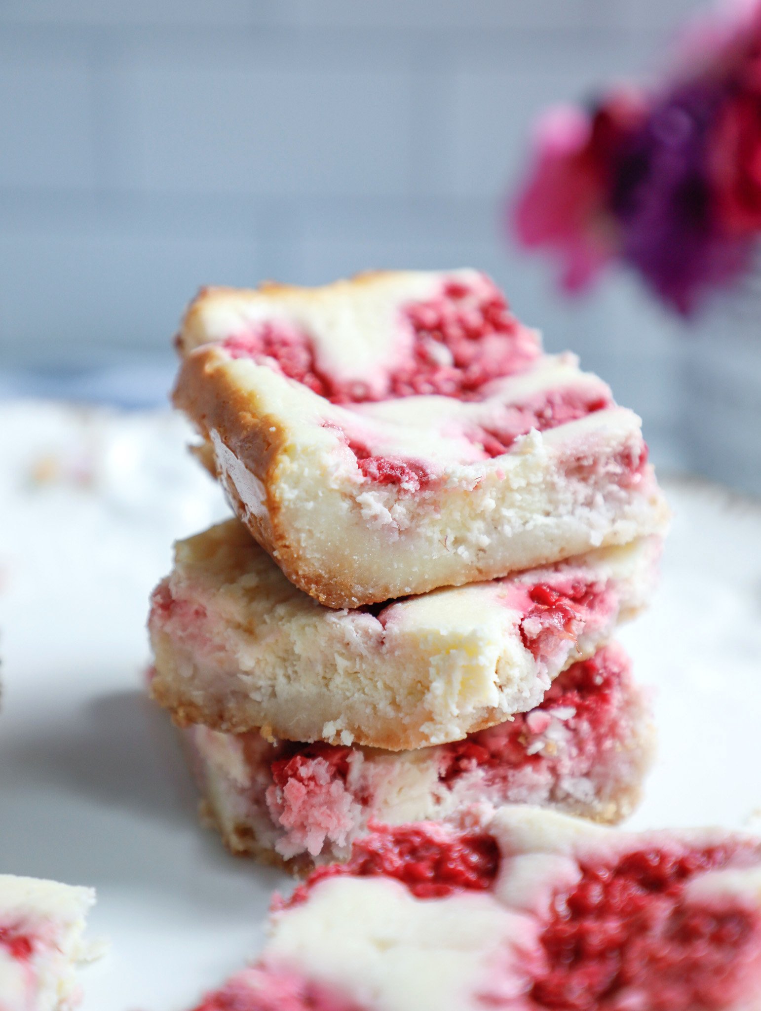 three keto raspberry cheesecake bars stacked on top of each other