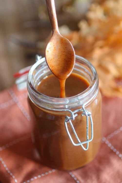 Mason jar full of keto pumpkin pie spice syrup and dripping spoon