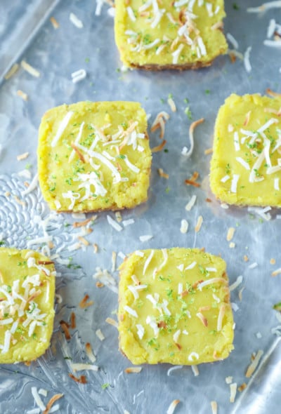 Keto Coconut Lime Bars sprinkled with coconut on a grey background