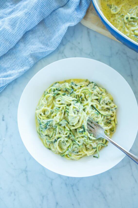 Easy Four Cheese Pesto Zoodles in a white bowl with fork twirl
