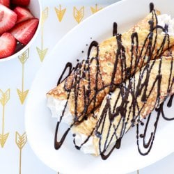 Keto Cannoli Stuffed Crepes on white tray with gold arrows