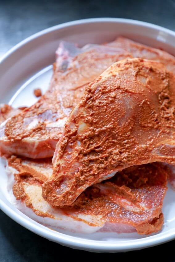 Keto Pork Chops al Pastor - raw pork marinating in white dish