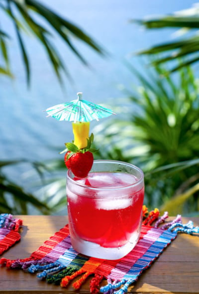 Easy Keto Rum Punch with strawberry and pineapple garnish
