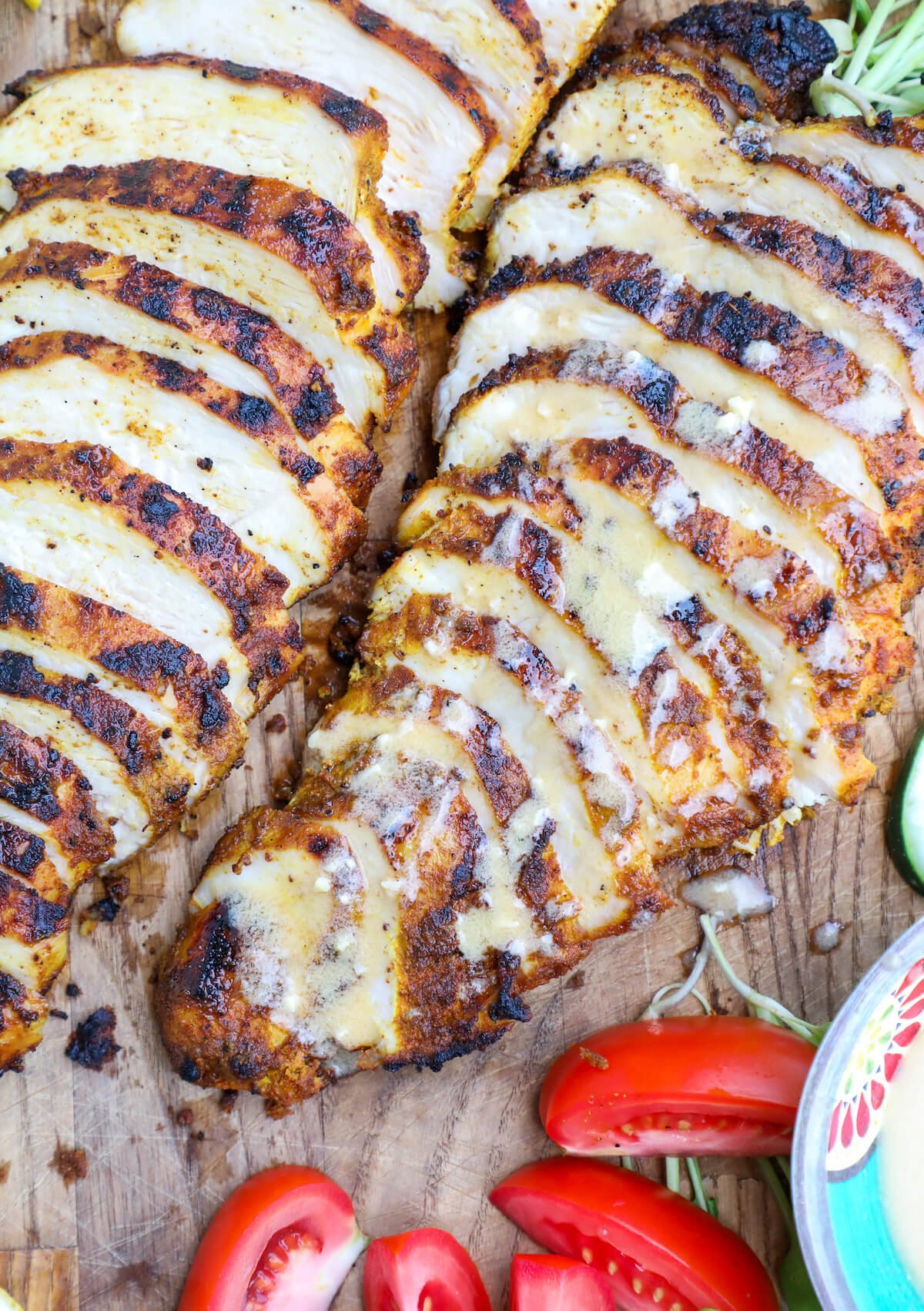 Close up photo of grilled sliced chicken breast with a tahini dressing drizzled over the top.