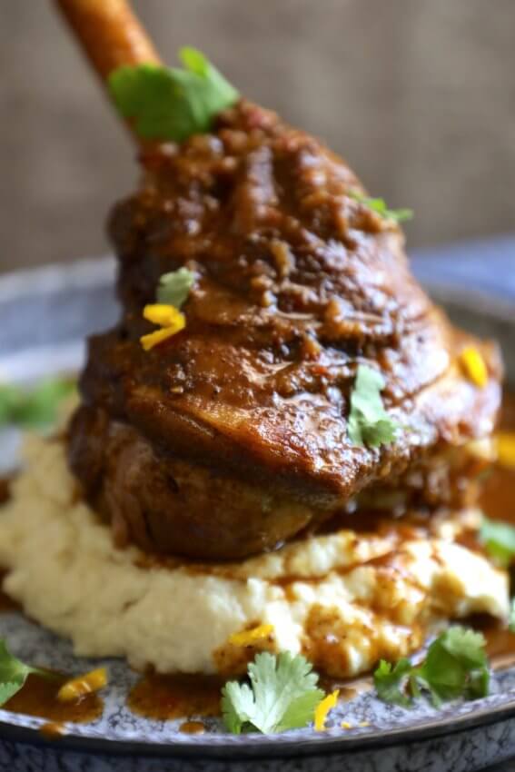 Close up side view of a lamb shank on a bed of cauliflower mash