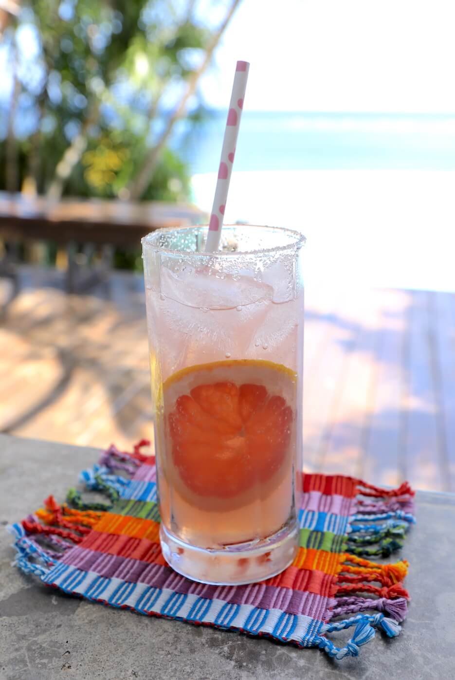 Keto Paloma Cocktail with grapefruit slice garnish and pool in background