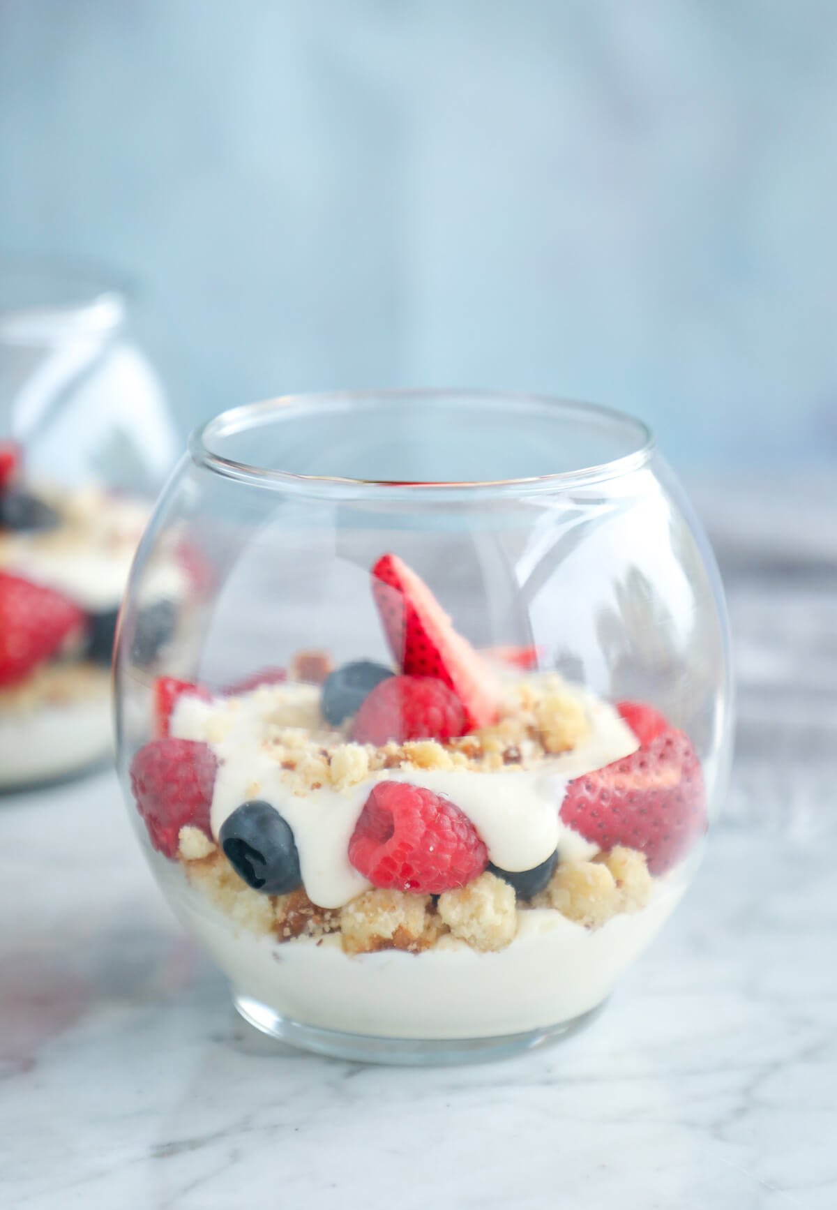 Keto No Bake Cheesecake Parfaits in a large round glass on a marble cutting board
