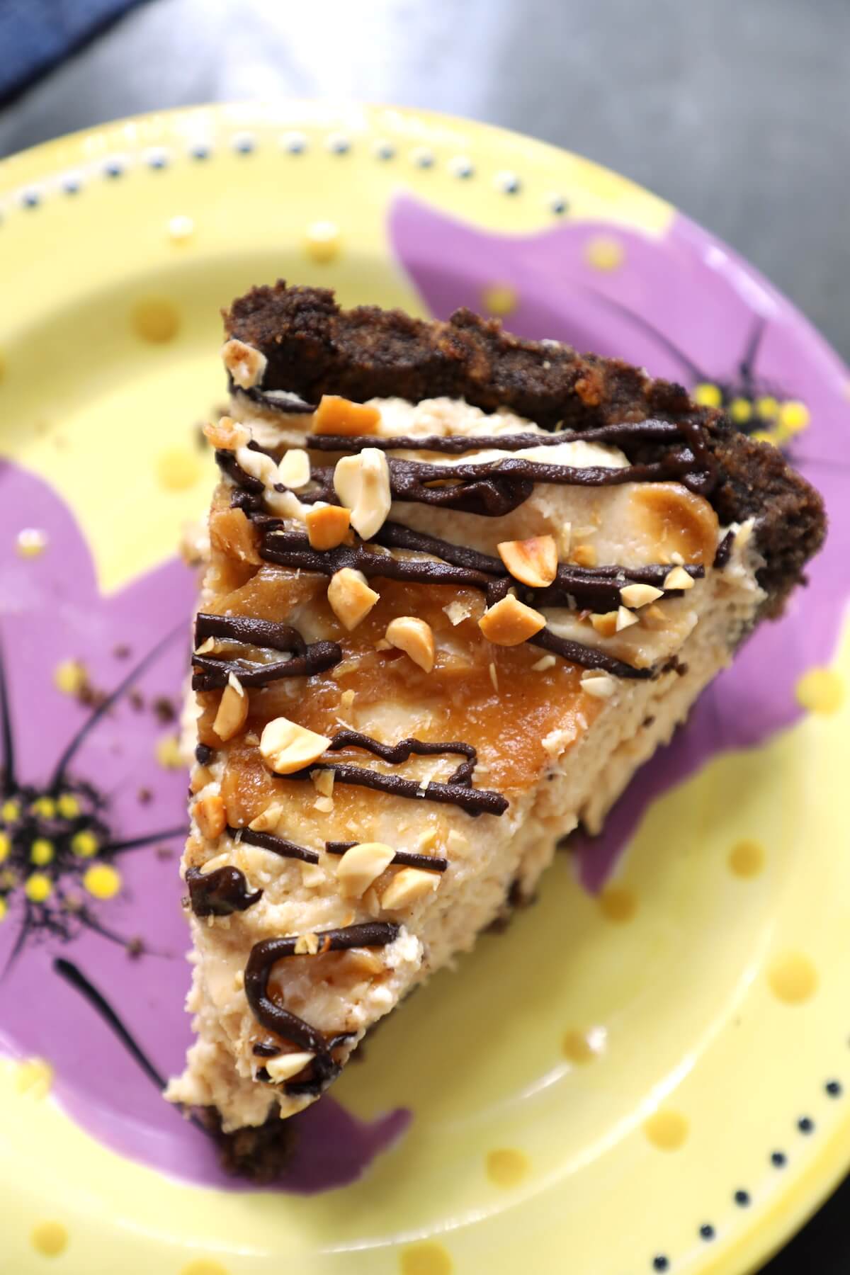 Top view of a slice of Keto Peanut Butter & Chocolate Pie on a yellow pottery plate with purple flowers on it. 