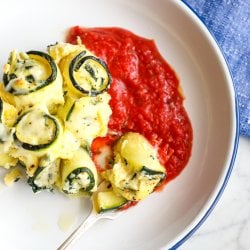 Keto Zucchini Rollatini on a white plate with a blue rim top view