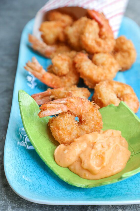 Keto Coconut Shrimp on a blue platter with a green plate of dipping sauce
