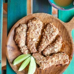 Keto Peanut Chicken Tenders on a wooden platter garnished with 3 lime wedges