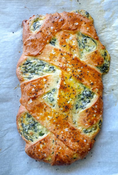 Cheesy Keto Spinach Calzone shown whole and on a parchment lined baking sheet