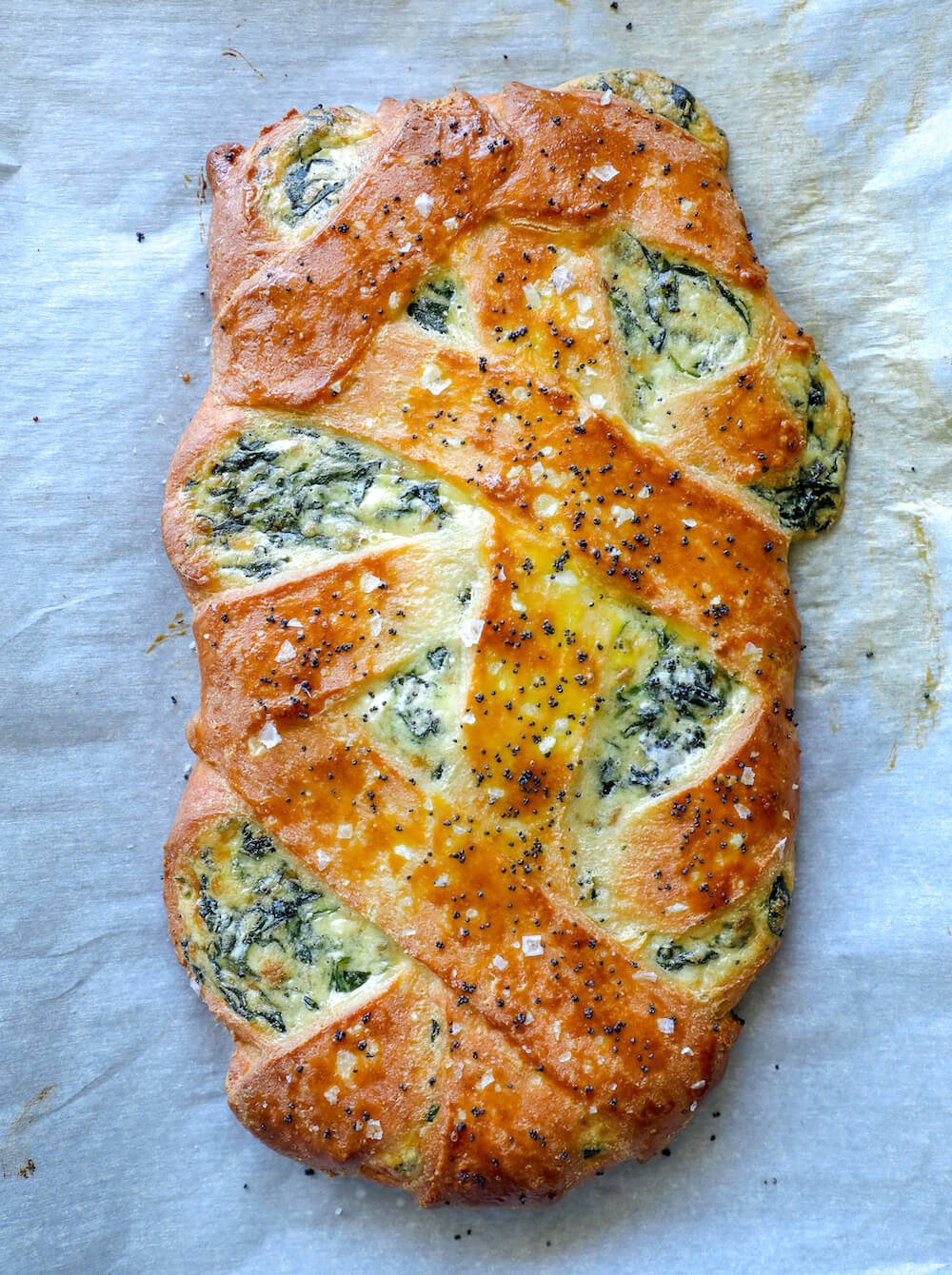 Cheesy Keto Spinach Calzone shown whole and on a parchment lined baking sheet