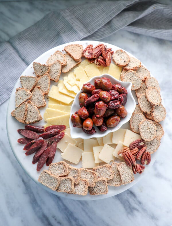 Keto HOP crackers on a marble cake plate with cheese, olives, and salami