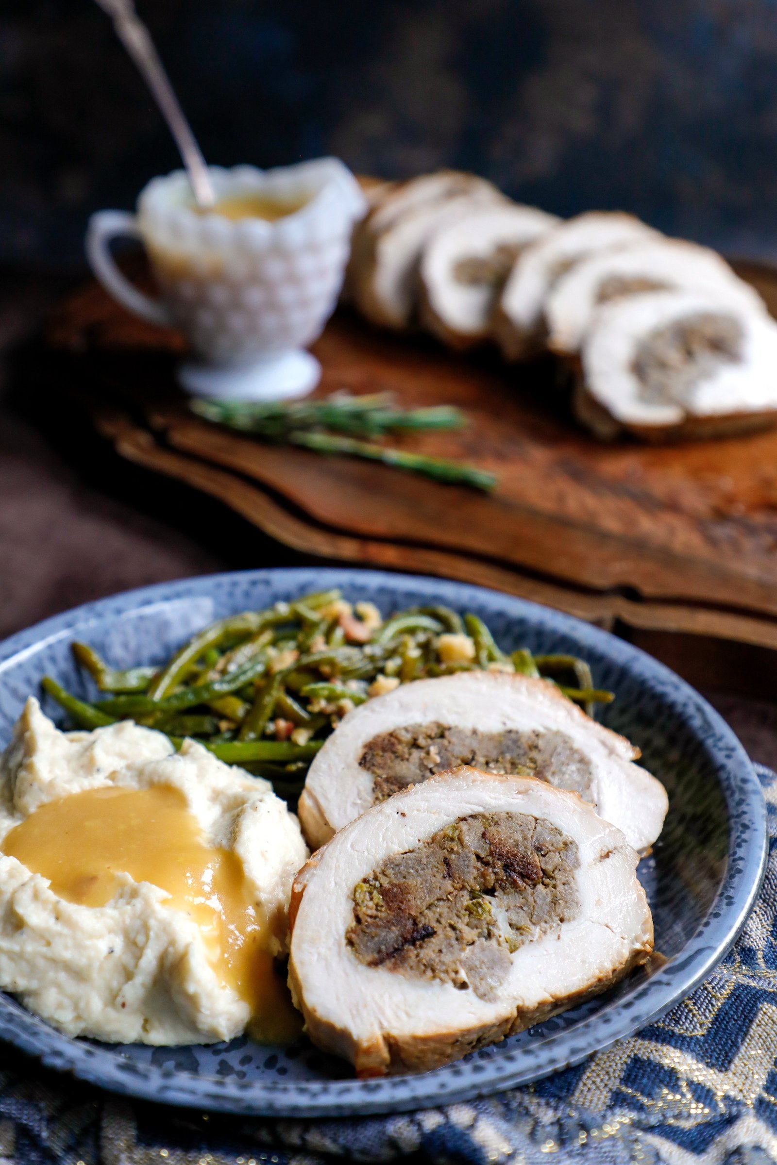 Slices of keto turkey roulade shown with green beans and cauliflower puree and turkey gravy