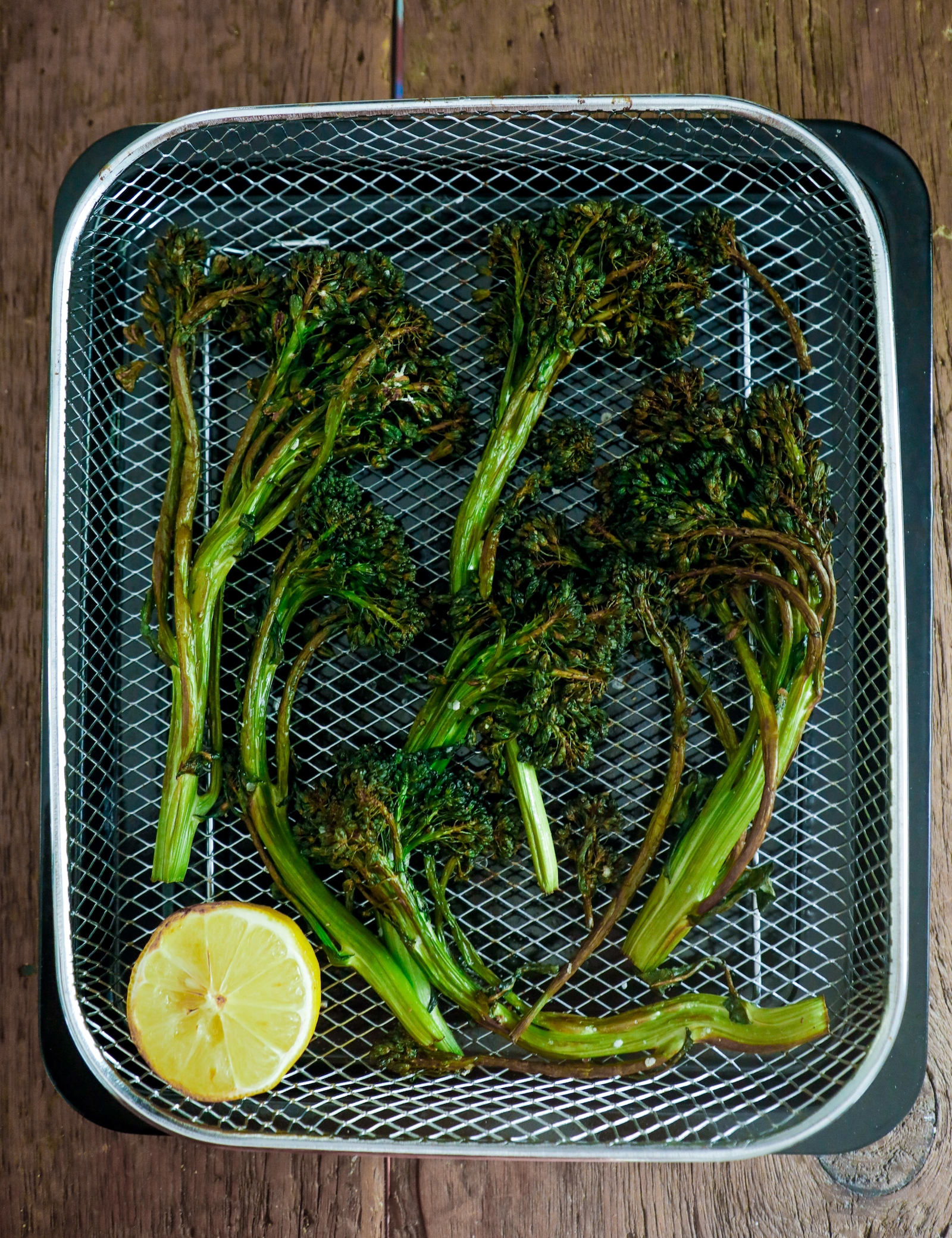 broccolini in the air fryer basket after cooking for 10 minutes at 400 degrees