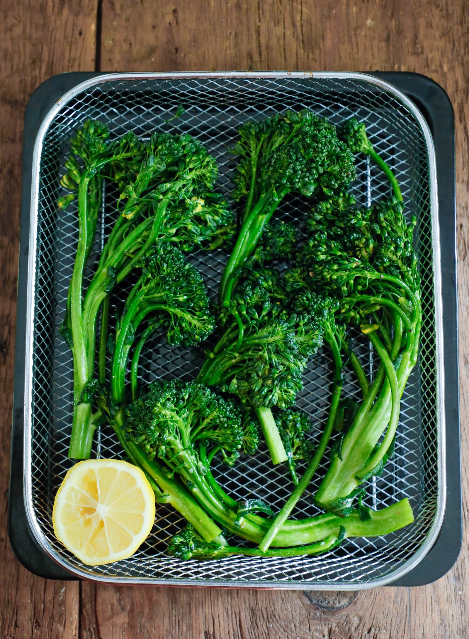 raw broccolini in the air fryer basket before cooking