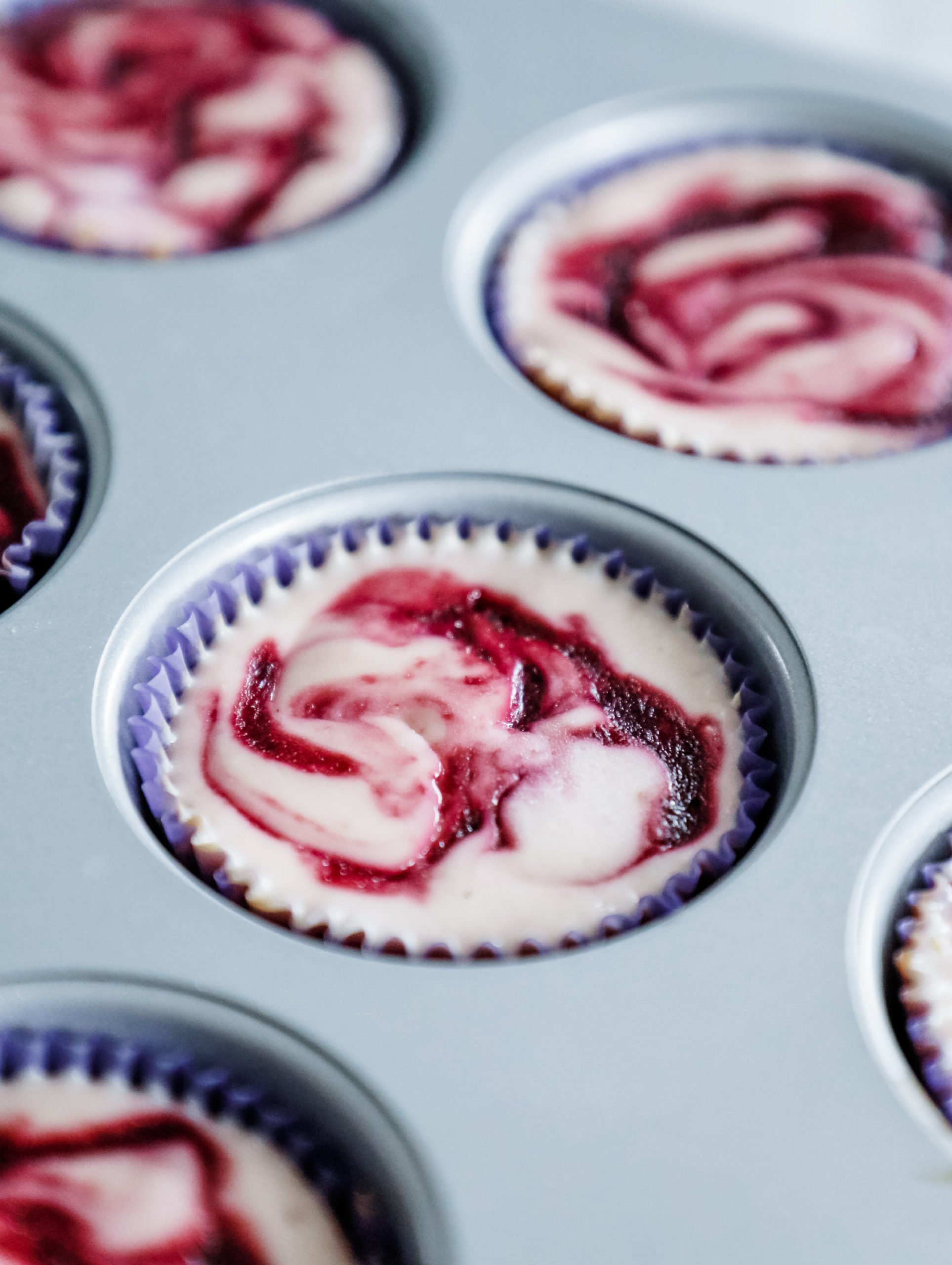 Blackberry cheesecake cup in a muffin lined muffin tin after baking.