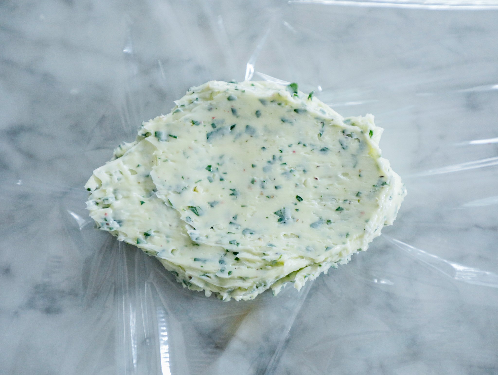 Maitre de butter spread onto plastic wrap