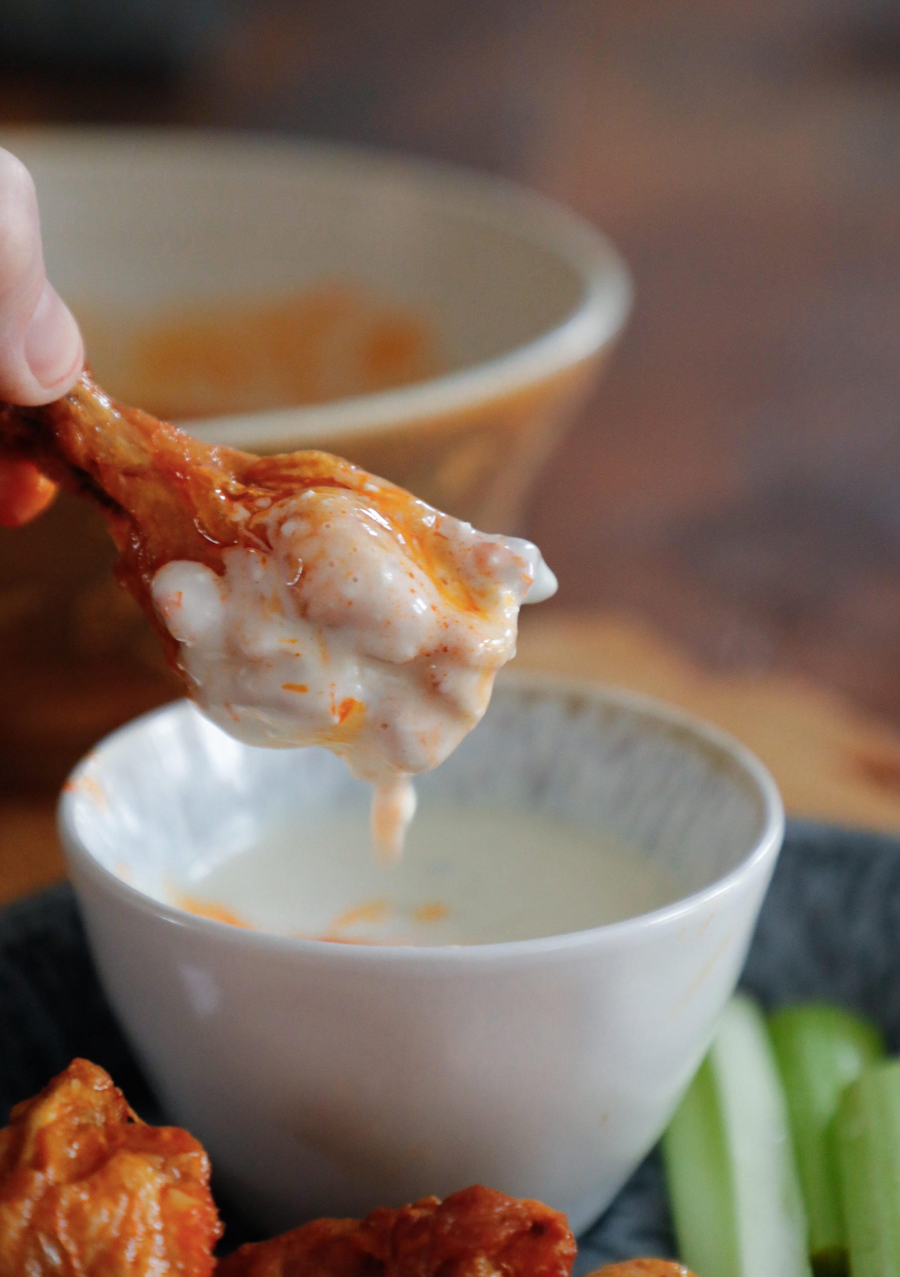 A buffalo wing dipped into a bowl of homemade blue cheese dressing