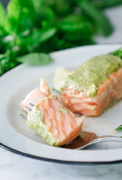 A forkful of salmon with basil pesto on it.