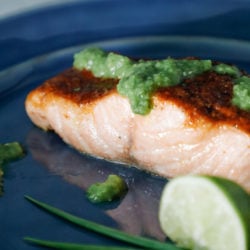 cajun salmon on a blue plate with salsa verde and a lime wedge