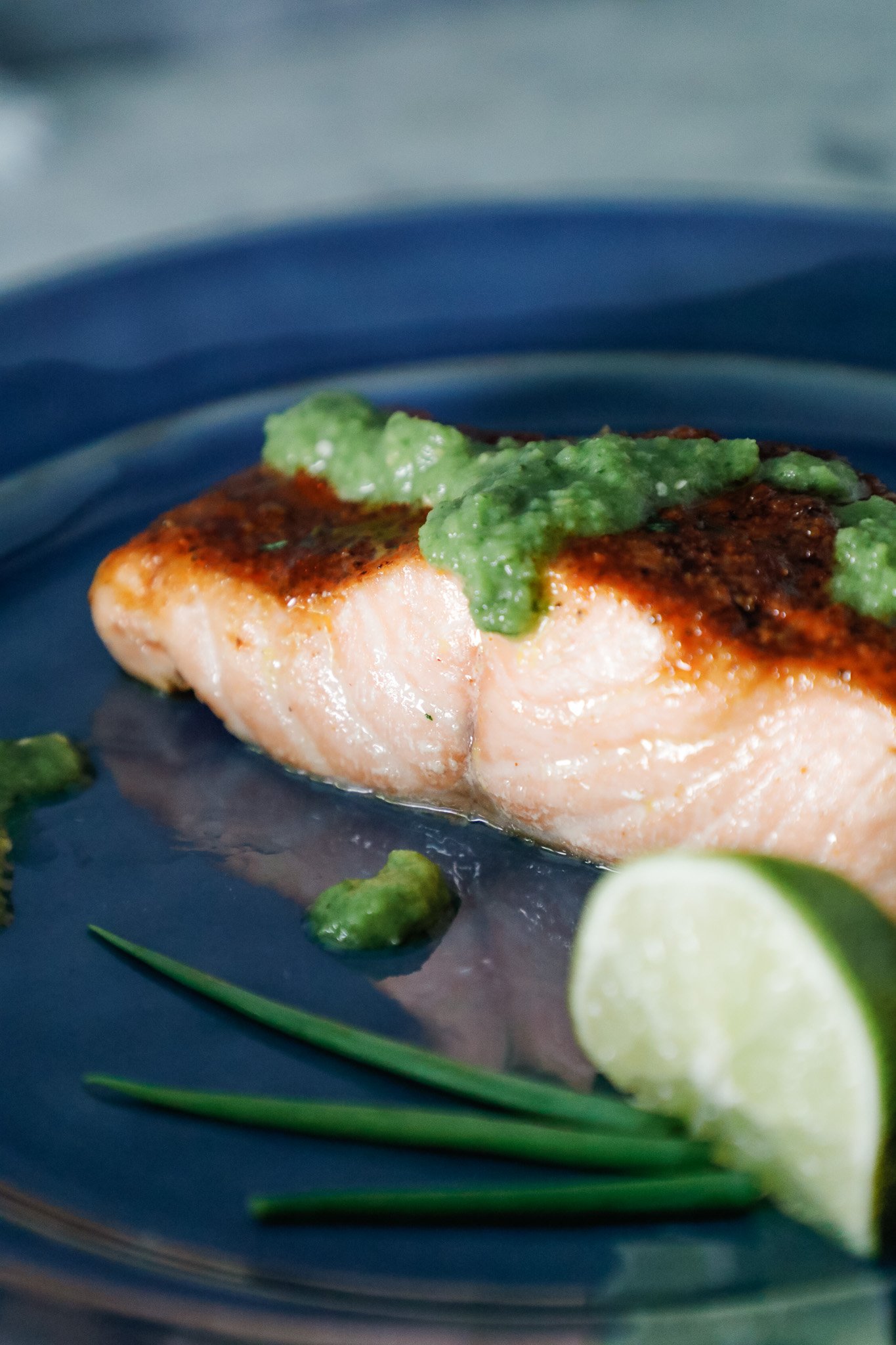 cajun air fryer salmon on a blue plate with salsa verde and a lime wedge