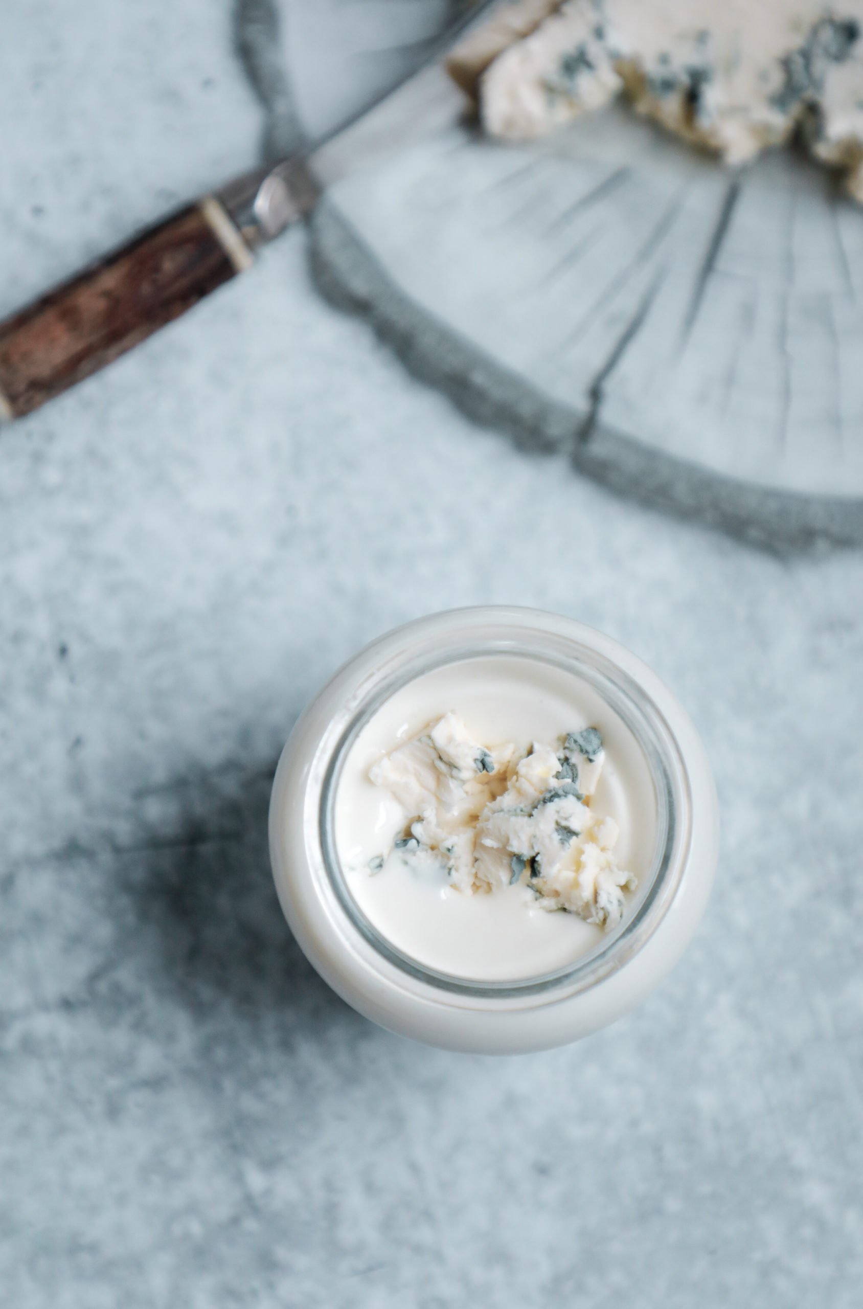 gorgonzola dressing in a glass jar with fresh blue cheese crumbled on top of it