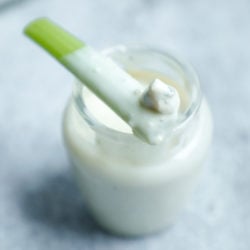 Keto Blue cheese dressing in a glass jar with a piece of celery on top that has been dipped into it
