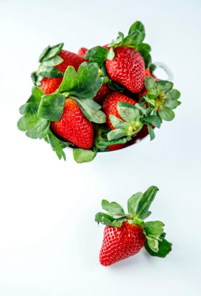 Fresh strawberries in a white colander on a white background